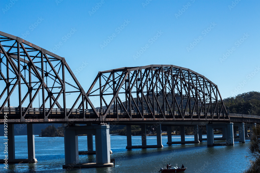 Fototapeta premium Metal bridge spanning Hawkesbury River at Brooklyn Australia against blue water and clear blue sky