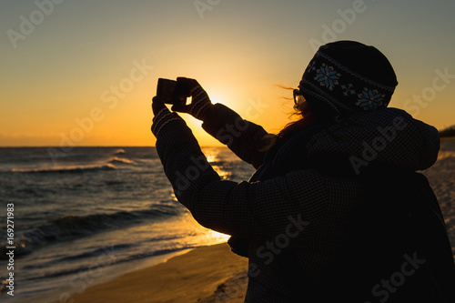 Woman takes a picture on phone. South Korea, Gangneung, coast of Japan sea.