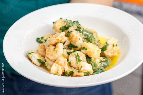 Spicy seafood shrimp fried with green spices and olive oil on white plate