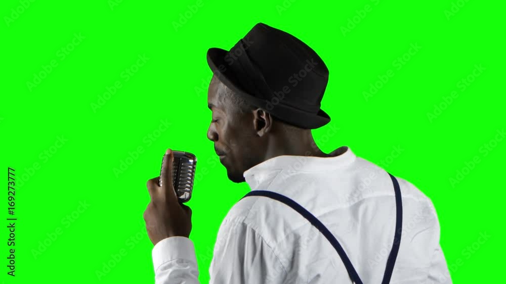 Man african american the view from the back standing at the microphone professionally singing in a recording studio. Green screen. Close up Man african american the view from the back standing at the microphone professionally singing in a recording studio. Green screen. Close up