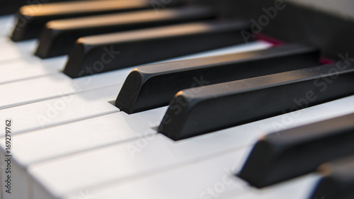 Dettaglio dei tasti di un pianoforte antico ma ristrutturato e rimesso a nuovo. La tastiera è composta da 88 tasti, di colore bianco e nero, sui quali si riflettono i colori caldi del tramonto.
