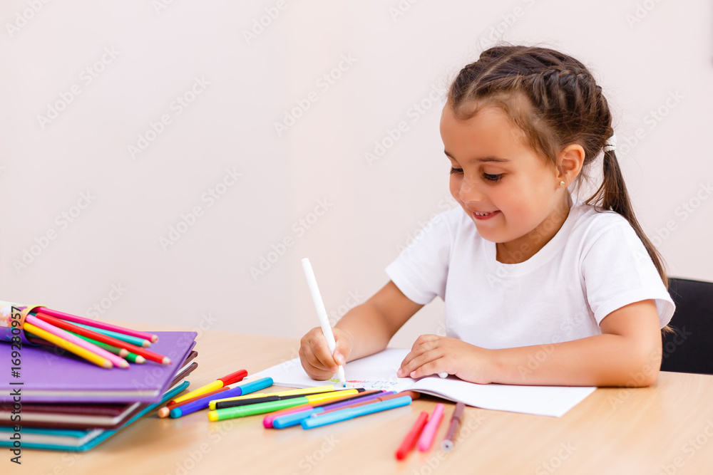 happy cute little girl doing school homework studying in living room at home and writing english class notebook learning knowledge. happy cute little girl doing school homework studying in living room at home and writing english class notebook learning knowledge.