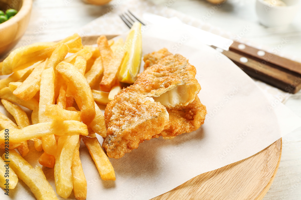 Tasty fried fish and chips on wooden board Tasty fried fish and chips on wooden board
