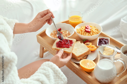 Young beautiful woman having breakfast on bed