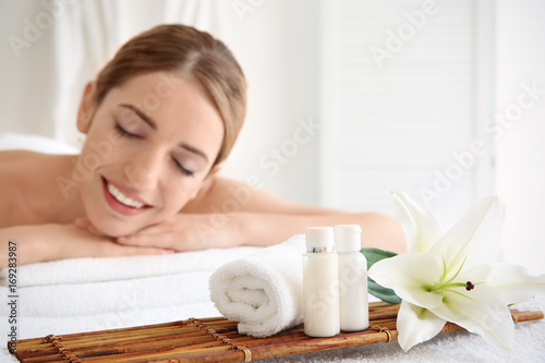 Spa set with cosmetics and young woman on background in salon