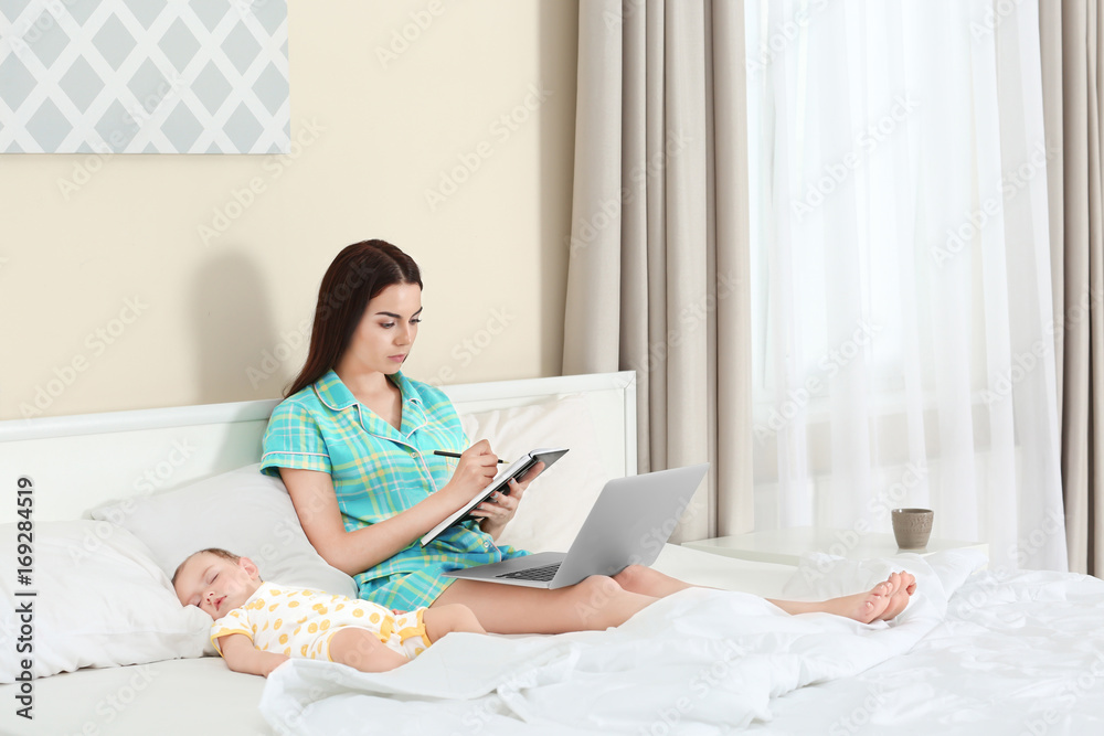 Young mother working near sleeping baby in bedroom Young mother working near sleeping baby in bedroom