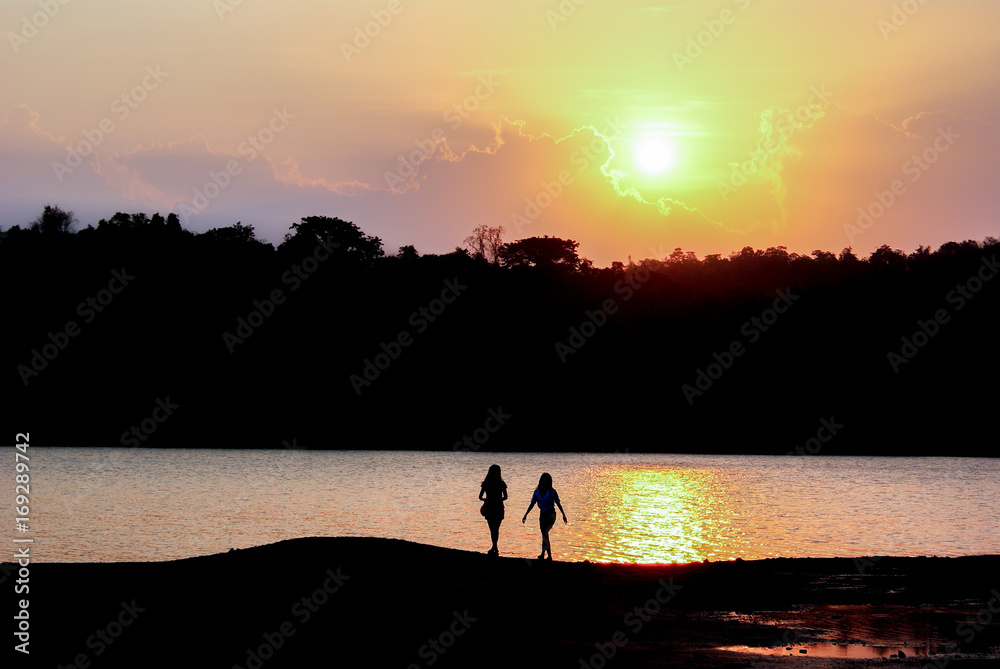 Silhouette lovely couple standing and looking silhouette view of lake and mountain in sunset or sunrise. Sunshine with landscape view and traveler in twilight time.