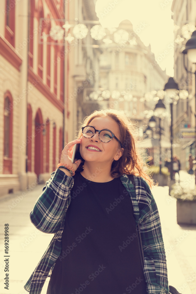 Fototapeta premium Modern girl talking on her cellphone outdoors.