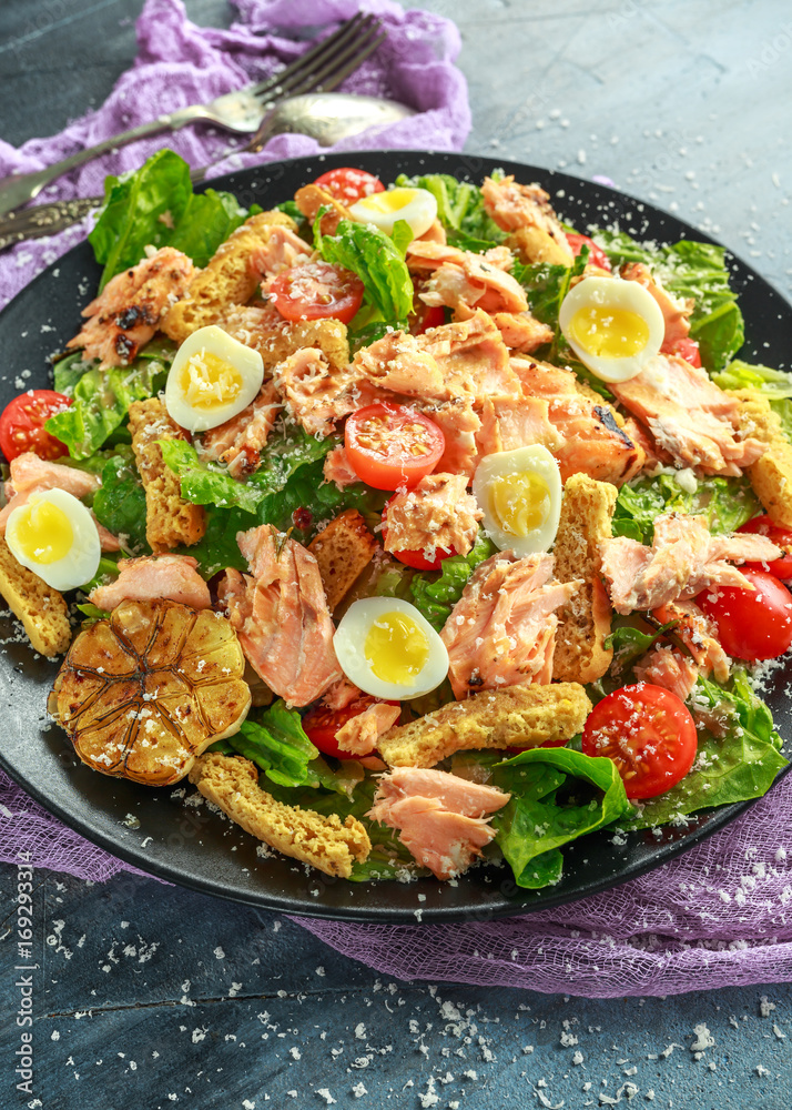 Cesar salad with salmon, cherry tomatoes, garlic, crutons, romaine lettuce and parmesan.