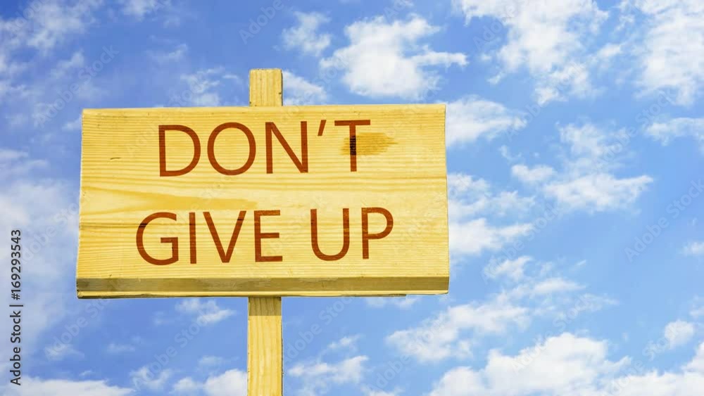 Don't give up. Words on a wooden sign against time lapse clouds in the blue sky. 