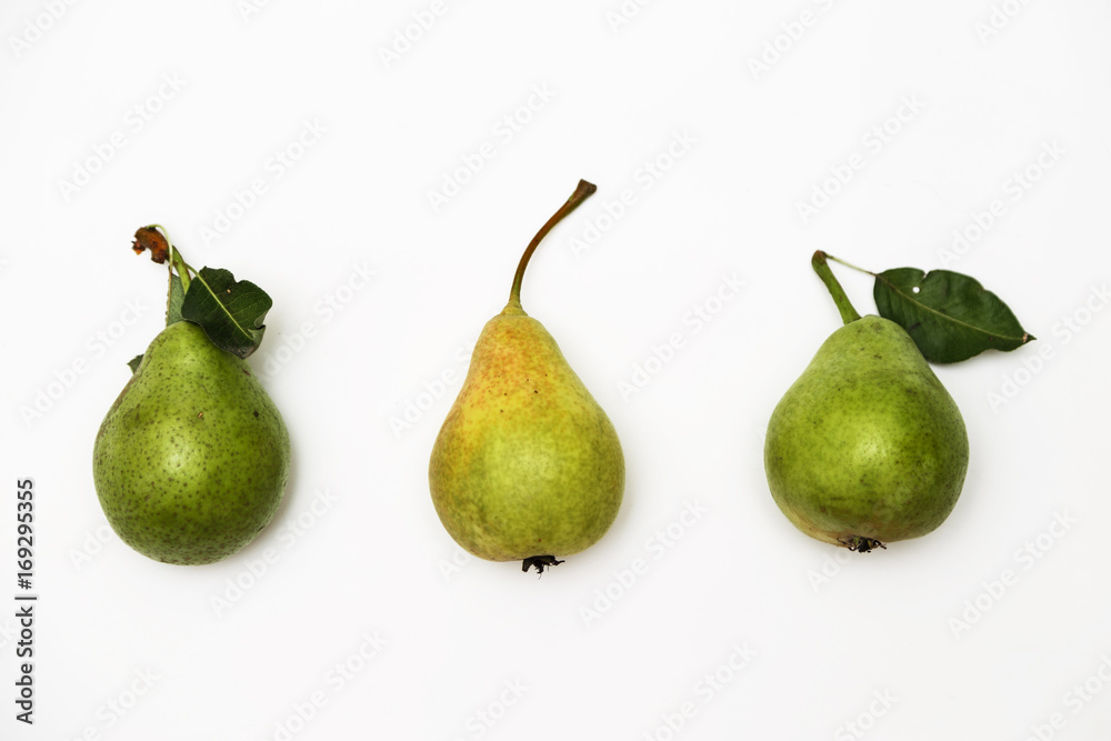 Three ripe green pears with a sprig lying in a row isolated on a white background. Top view Three ripe green pears with a sprig lying in a row isolated on a white background. Top view