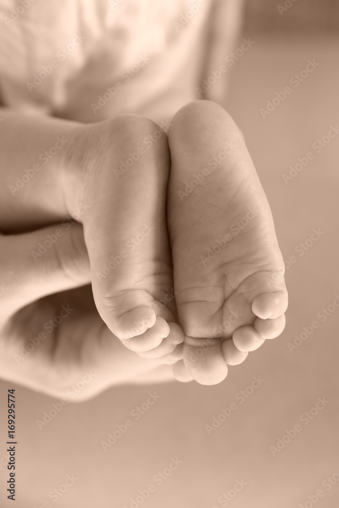 Small feet of the newborn in the hand of the parent.