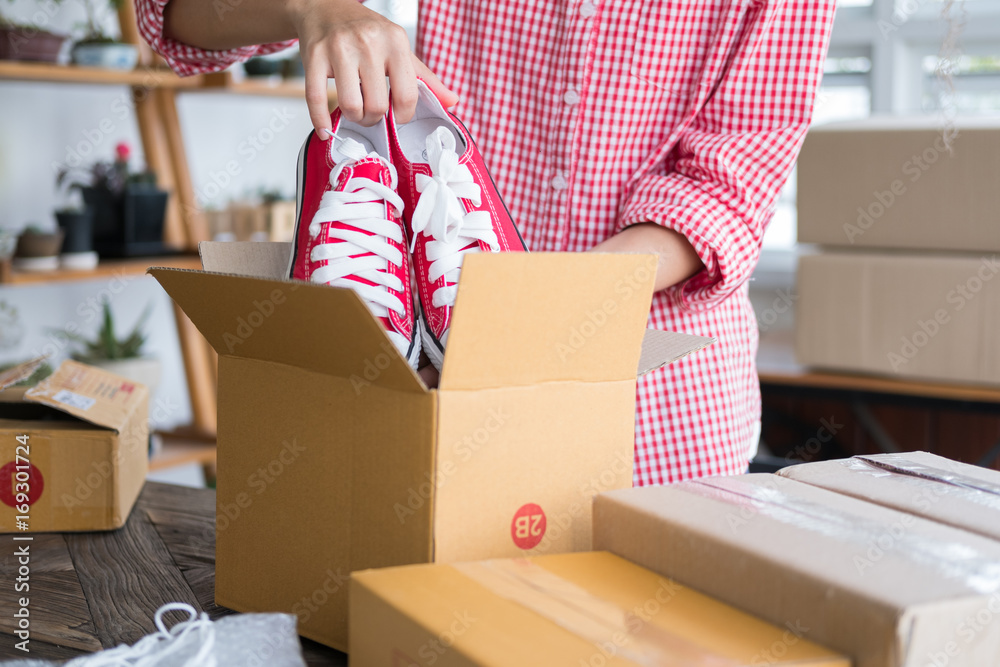 business owner packing shoes in the box at workplace. freelance woman seller prepare product for packaging process at home. Online selling, internet marketing, e-commerce concept business owner packing shoes in the box at workplace. freelance woman seller prepare product for packaging process at home. Online selling, internet marketing, e-commerce concept