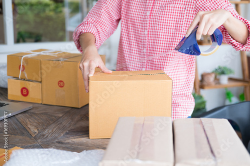 business owner packing cardboard box at workplace. freelance woman seller prepare parcel box of product for deliver to customer. Online selling, internet marketing, e-commerce, shipping concept