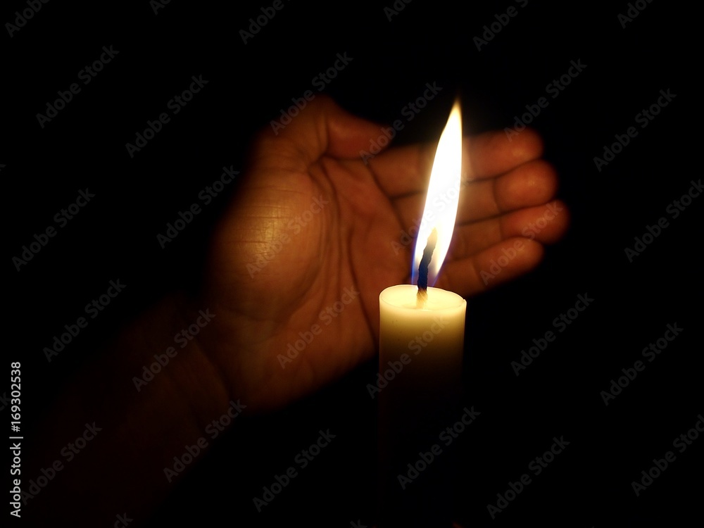 Hand covering flame of candle from wind Hand covering flame of candle from wind