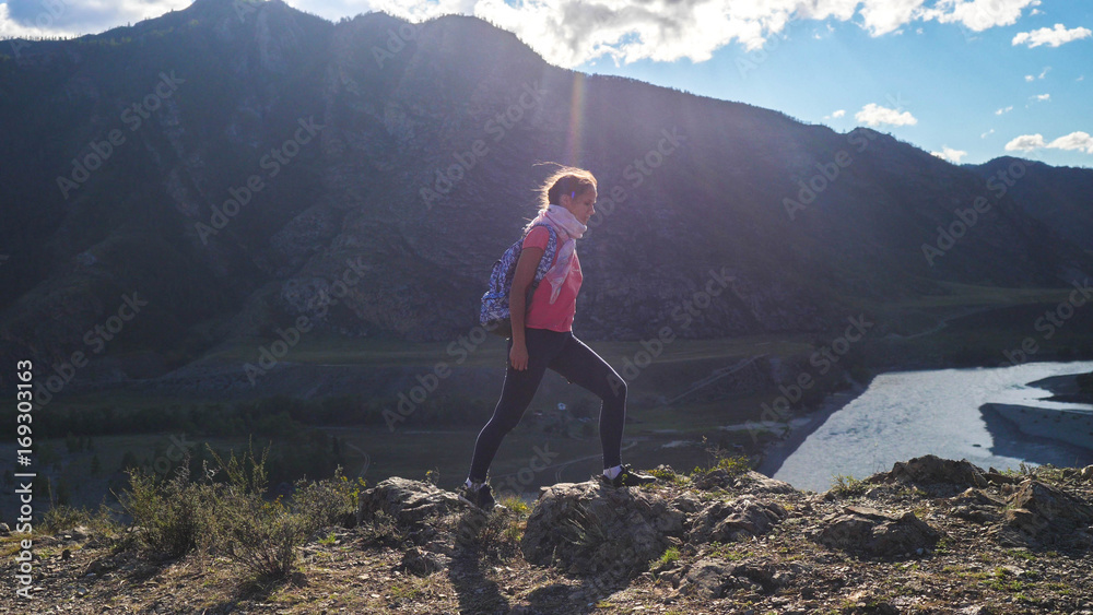 Obraz premium Hiker with backpack hiking on top of a mountain with sun flares. Young woman healthy active lifestyle. Adventure in Nature.