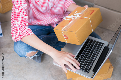 start up small business owner checking product order with computer at workplace. freelance woman seller prepare parcel box for deliver to customer.  Online selling, e-commerce, shipping concept