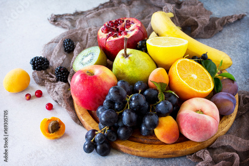 Fresh mixed fruits on a gray stone or slate background. The concept of a healthy diet.