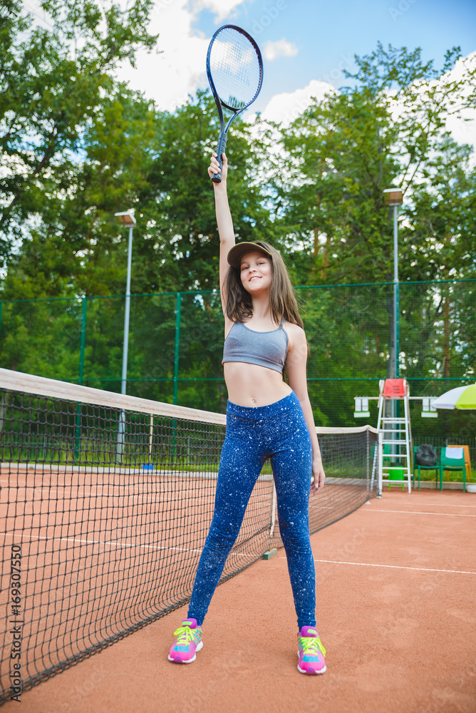 Cute girl playing tennis and posing in court outdoor