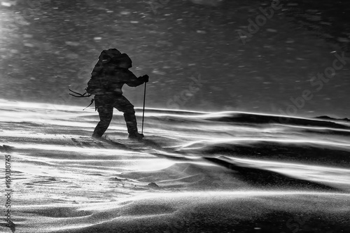 Climber fights with bad weather in the winter mountains