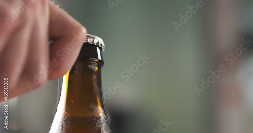 man hand opening brown beer bottle closeup