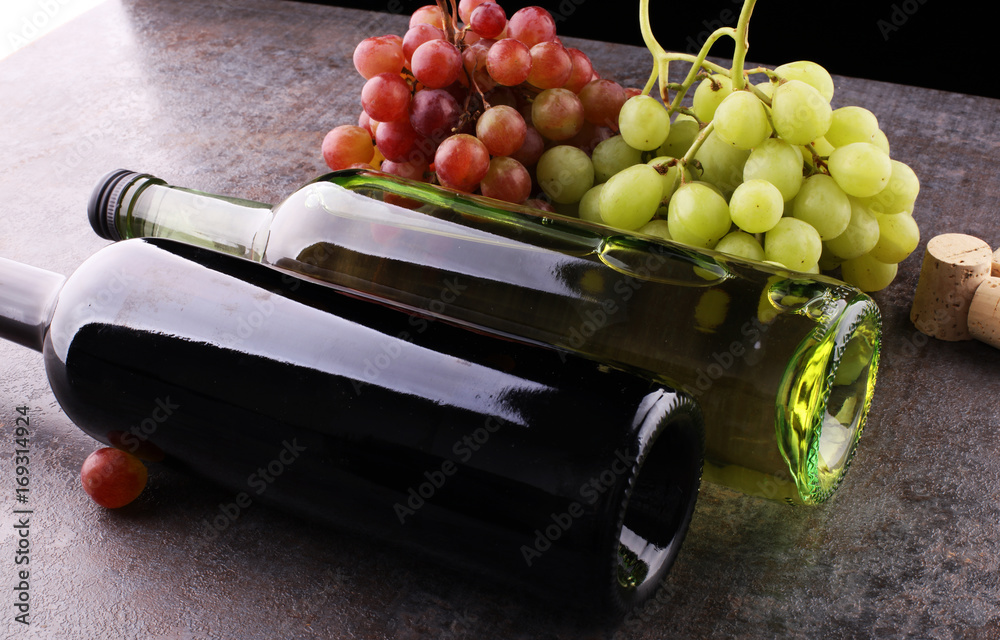 Obraz premium Bottle of white and red wine, grape and corks on wooden table