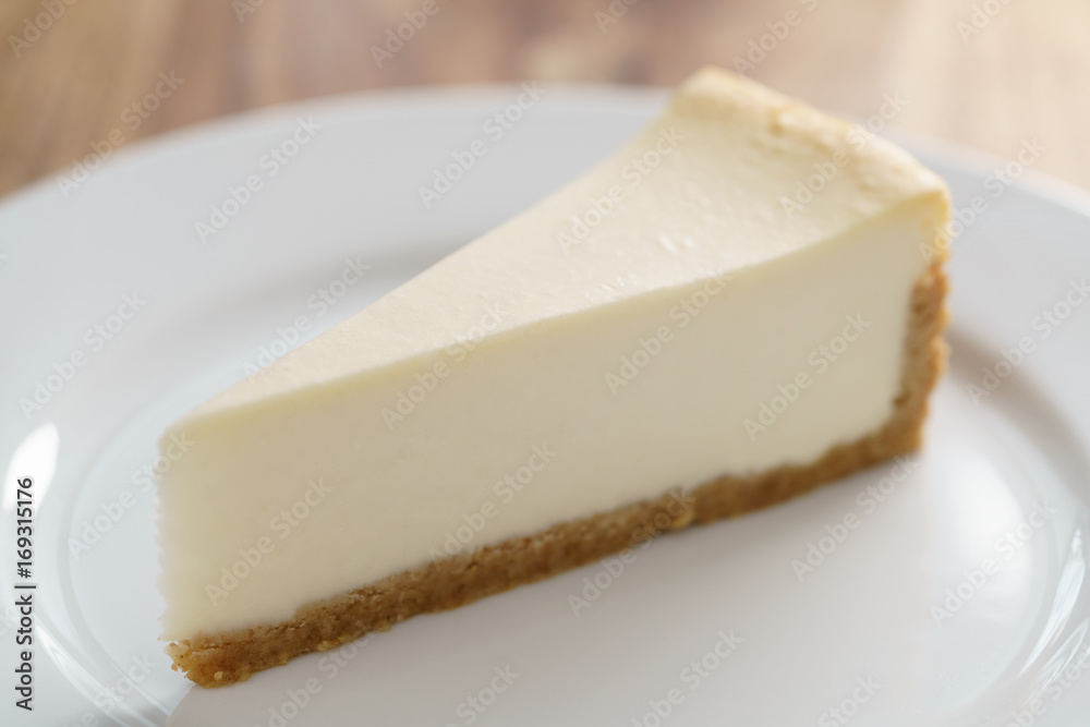 slice of traditional new york cheesecake on white plate on wood table slice of traditional new york cheesecake on white plate on wood table