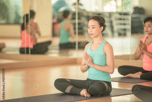 fitness, sport, training, yoga and people concept - Asian woman do exercise in gym.Group Of female Doing Yoga Indoors meditating,