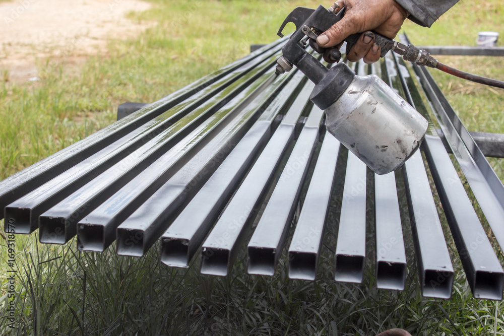 Painter painting steel pole silvers to black color by sprayer. Stock