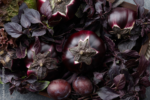 Fotografie Wooden tray with purple vegetables and herbs on stone textured background