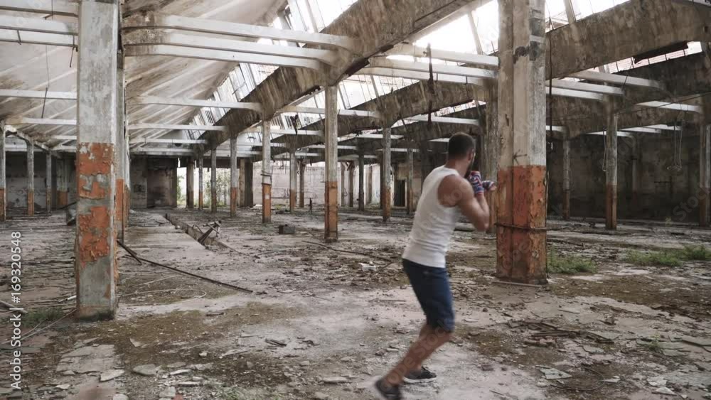 Back view of male boxer doing shadow boxing exercise in an old abandoned building. Back view of male boxer doing shadow boxing exercise in an old abandoned building.