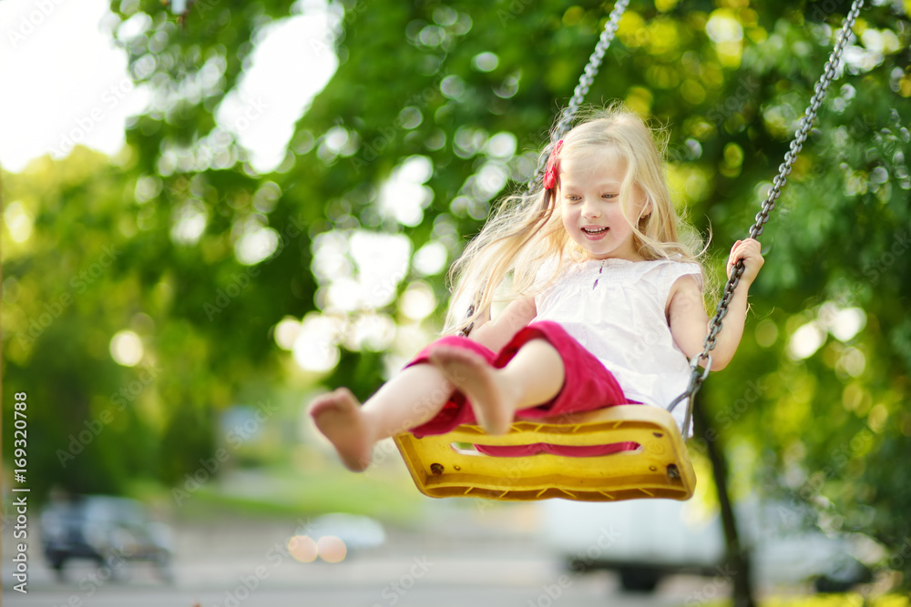 Cute little girl having fun on a playground outdoors on warm summer day Cute little girl having fun on a playground outdoors on warm summer day