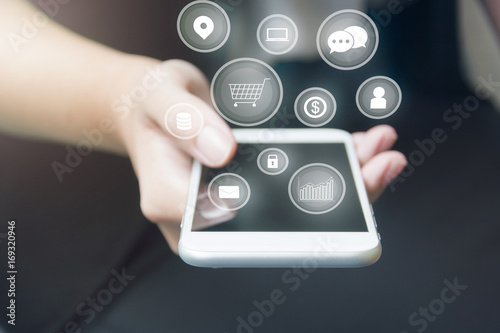Hand of businesswoman touching smartphone with popup icons floating on cellphone after connected business world and applications in business , technology , finance  and communication concept