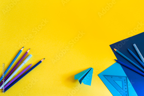 Creative, fashionable, minimalistic, school or office workspace with blue supplies on yellow background. Flat lay.