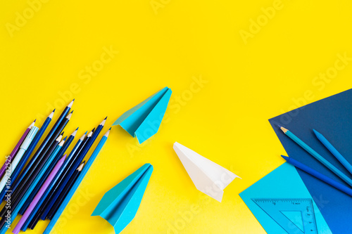 Creative, fashionable, minimalistic, school or office workspace with blue supplies on yellow background. Flat lay.