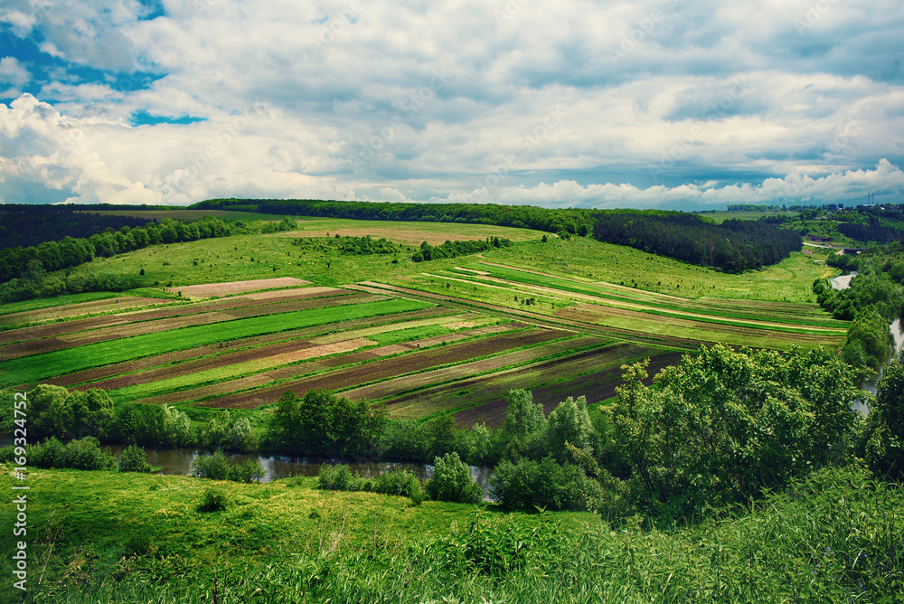 Fototapeta premium Rural landscape with fields, waves and blue sky with clouds, spring seasonal natural background