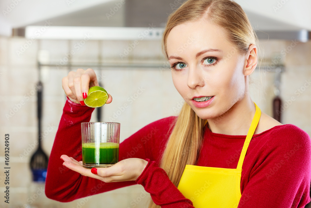 Woman in kitchen holding vegetable smoothie juice Woman in kitchen holding vegetable smoothie juice