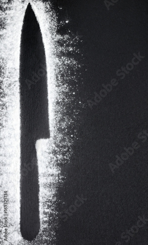 Knife silhouettes with flour on black shale background photo