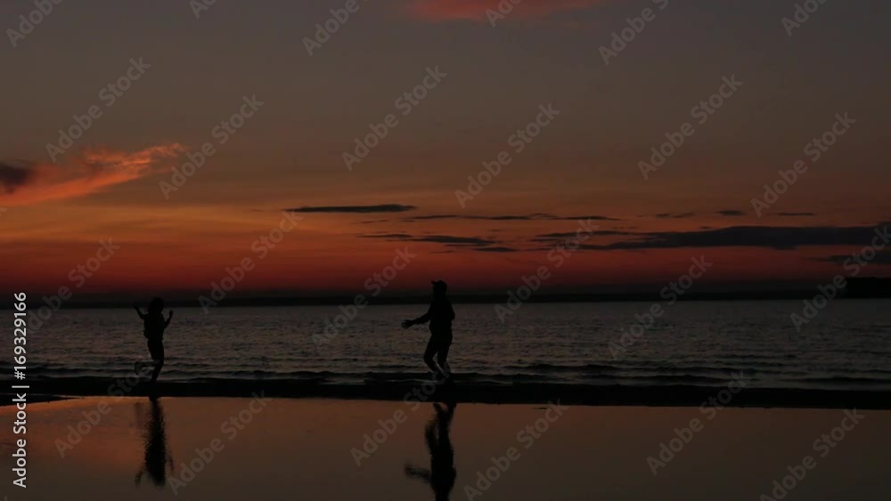 Silhouetted man and woman enjoy sunset at beach Silhouetted man and woman enjoy sunset at beach