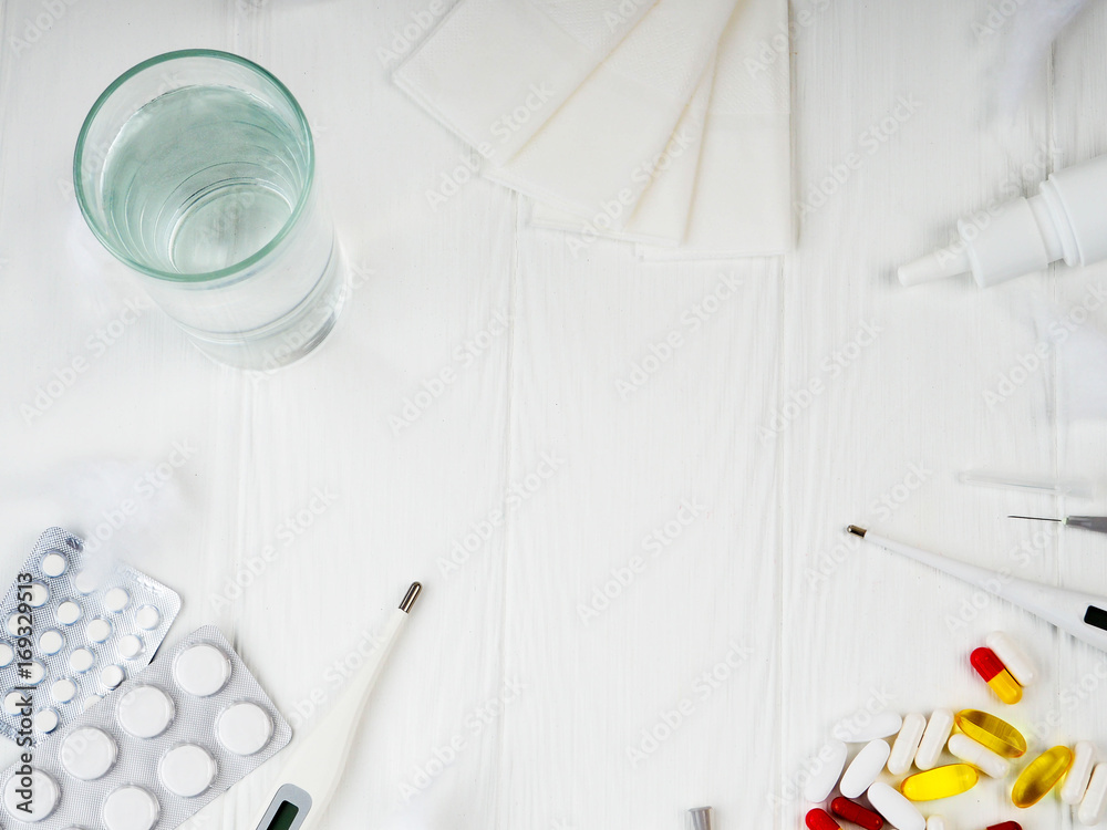 a glass of water, pills, thermometer, paper napkins on white wooden background, Top view, copy space. Medicine concept photo. High angle view, flat lay a glass of water, pills, thermometer, paper napkins on white wooden background, Top view, copy space. Medicine concept photo. High angle view, flat lay