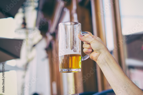 Woman holding a half-drunk glass of beer in an outdoor pub