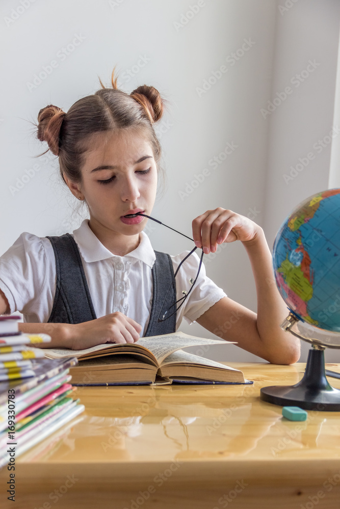 A schoolgirl at a table with textbooks. Day of knowledge. Back to school and homework concept A schoolgirl at a table with textbooks. Day of knowledge. Back to school and homework concept