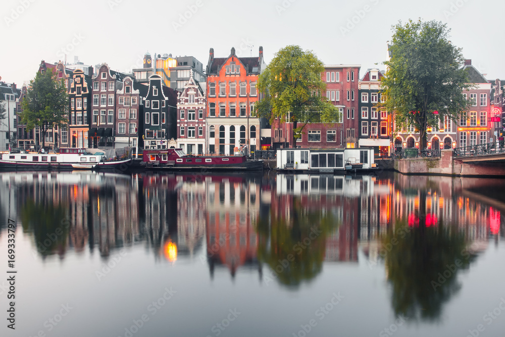 Amsterdam canal Amstel with typical dutch houses and houseboat from the boat in the morning, Holland, Netherlands.