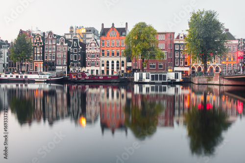 Amsterdam canal Amstel with typical dutch houses and houseboat from the boat in the morning, Holland, Netherlands.