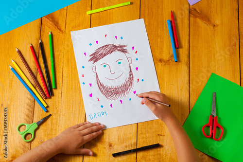 Child draws a portrait of his dad on father's day. The little boy did the drawing with pencil and marker. photo