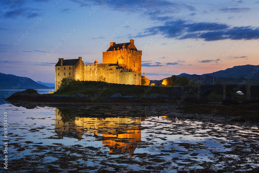 Eilean Donan Castle at Kyle reflecting itself into the water of Loch Duich and loch Alsh, during evening low tide.