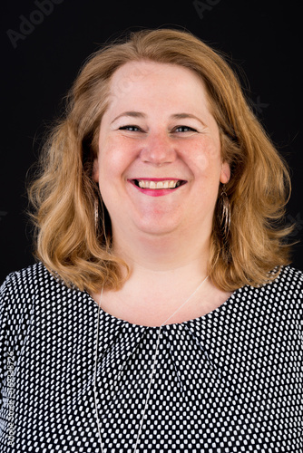 Portrait of a attractive european light overweighted red haired female in white black dress smiling friendly in front of black backgrouind