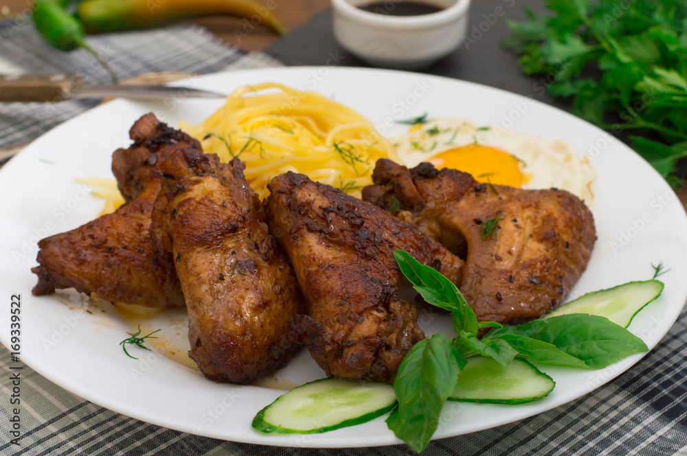 Fried chicken wings with spaghetti. Wooden background. Close-up. Top view Fried chicken wings with spaghetti. Wooden background. Close-up. Top view