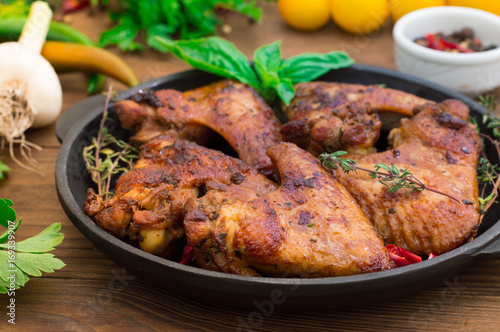 Baked chicken wings in baking pan. Selective focus. Wooden background. Close-up. Top view
