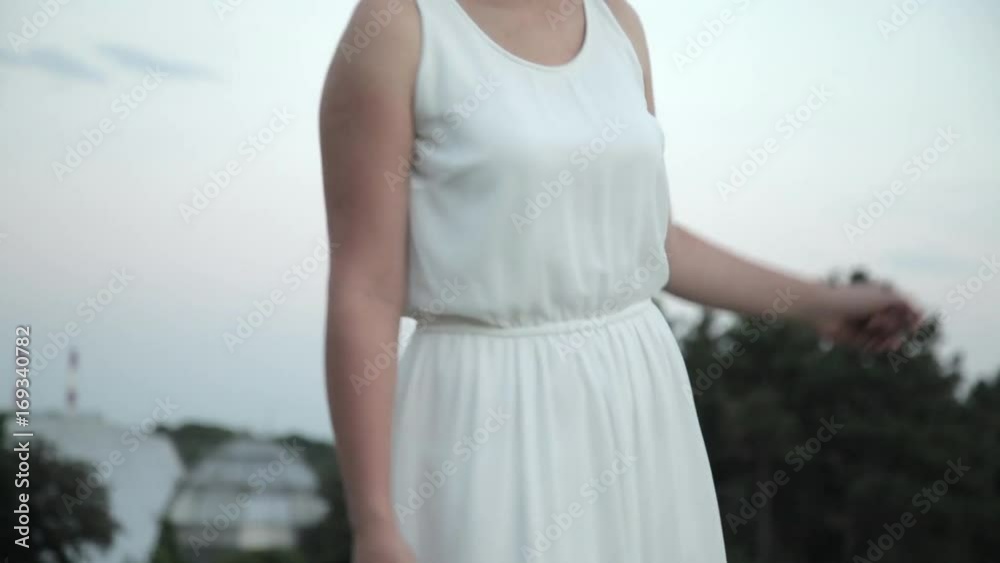 Young beautiful girl with flower circlet and white dress sings and dances outdoors at sunset. Young beautiful girl with flower circlet and white dress sings and dances outdoors at sunset.